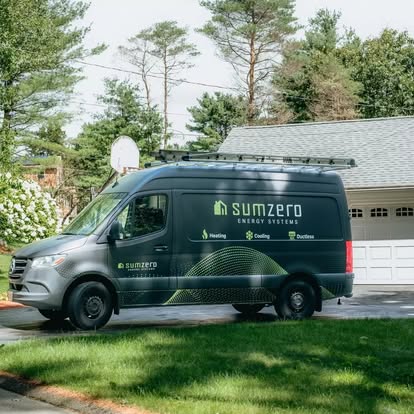 A van labeled "Sumzero Energy Systems" is parked on a driveway with a suburban house and trees in the background.